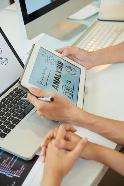 Crop shot of coworking people sitting at desk holding tablet with picture of Analysis concept