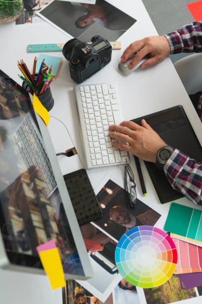 High angle view of mid section of Caucasian male graphic designer working on computer at desk in office. Modern casual creative business concept